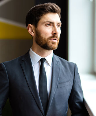 Hombre joven con traje elegante mirando por la ventana en oficina moderna, imagen de profesional ejecutivo y seguro