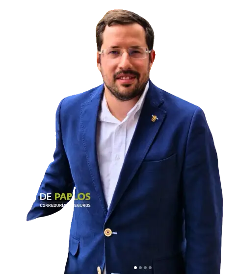 Carlos de Pablos, corredor de seguros, con gafas y chaqueta azul, posando de pie y sonriendo