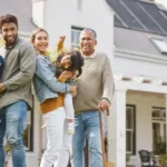 Familia de varias generaciones posando sonriente frente a una vivienda unifamiliar, representando la protección y seguridad del hogar con un seguro adecuado.