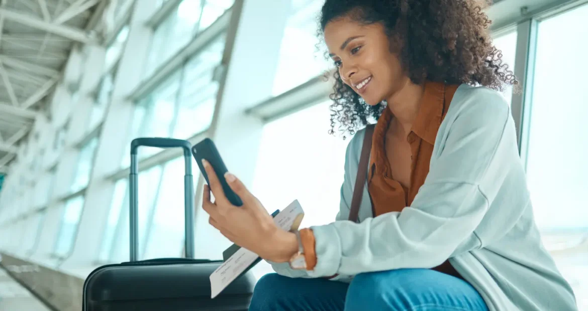 Un billete de viaje, un teléfono y una mujer negra en el aeropuerto, en una videollamada, esperando el avión y el vuelo.
