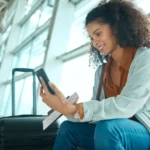 Un billete de viaje, un teléfono y una mujer negra en el aeropuerto, en una videollamada, esperando el avión y el vuelo.